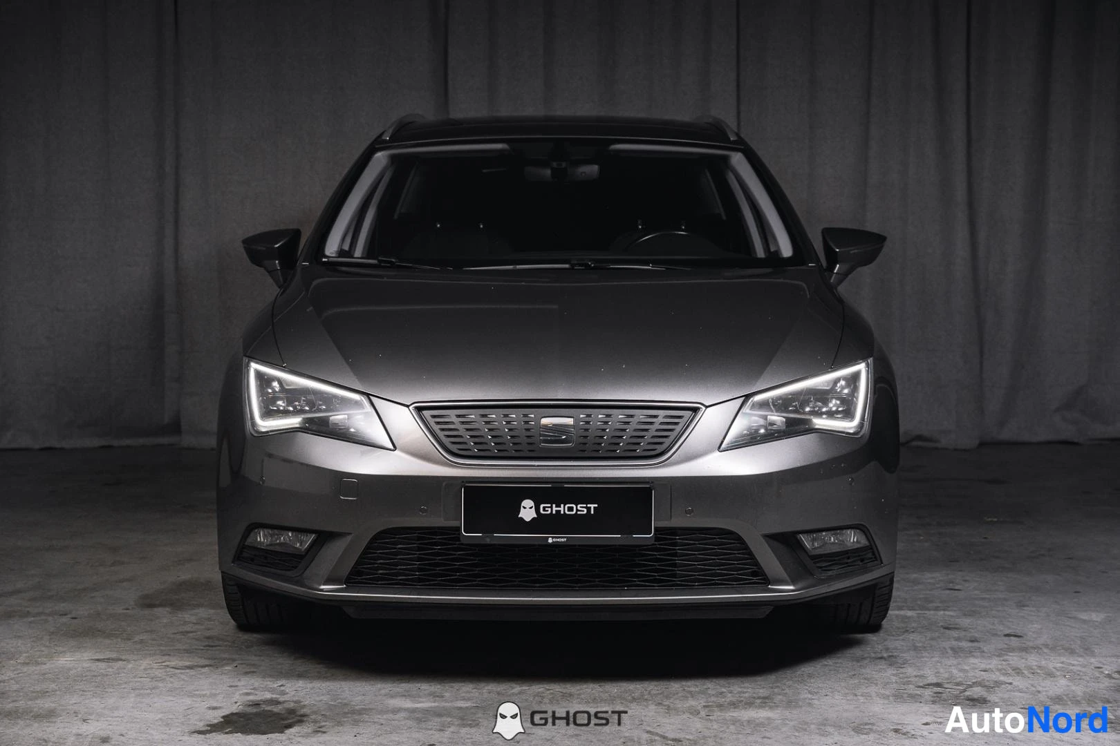 Edestä: Seat Leon ST suoraan edestä, tummanharmaa etupaneeli, LED-ajovalot ja rekisterikilven paikalla GHOST-tunnus