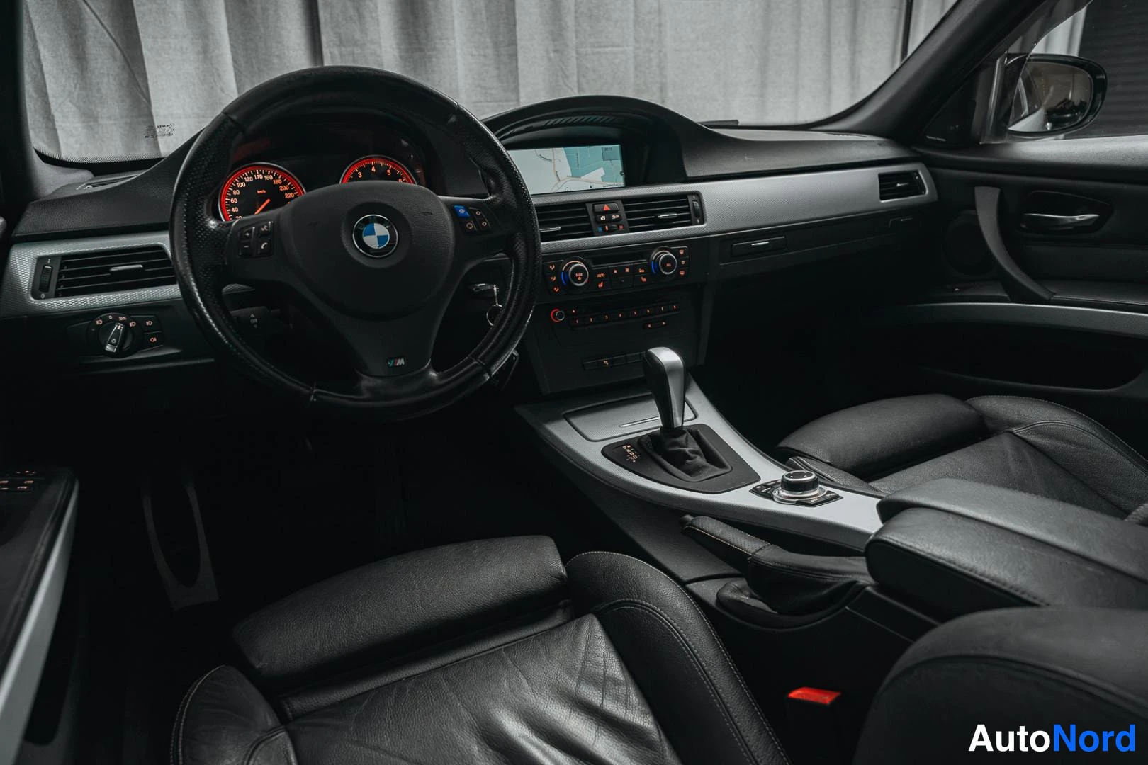 Muu: Ohjaamo kuljettajan puolelta: BMW-ohjauspyörä, analogiset mittarit, navigaationäyttö ja automaattivaihteiston valitsin.