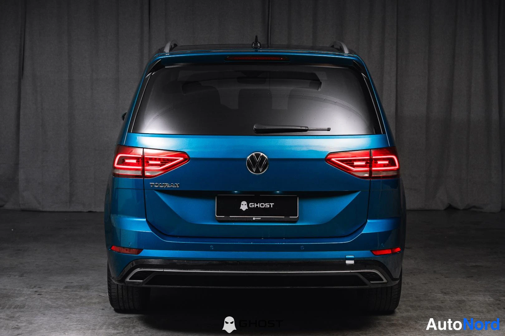 Takaa: Sininen Volkswagen Touran suoraan takaa, takaosa kokonaan näkyvissä.