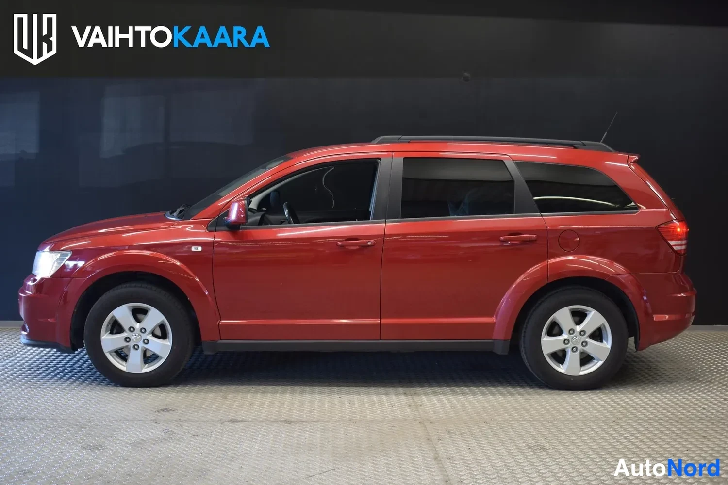 Etuviisto, nokka vasemmalle: Punainen Dodge Journey -farmariauto sivulta vasemmalta, yksi kylki näkyvissä.
