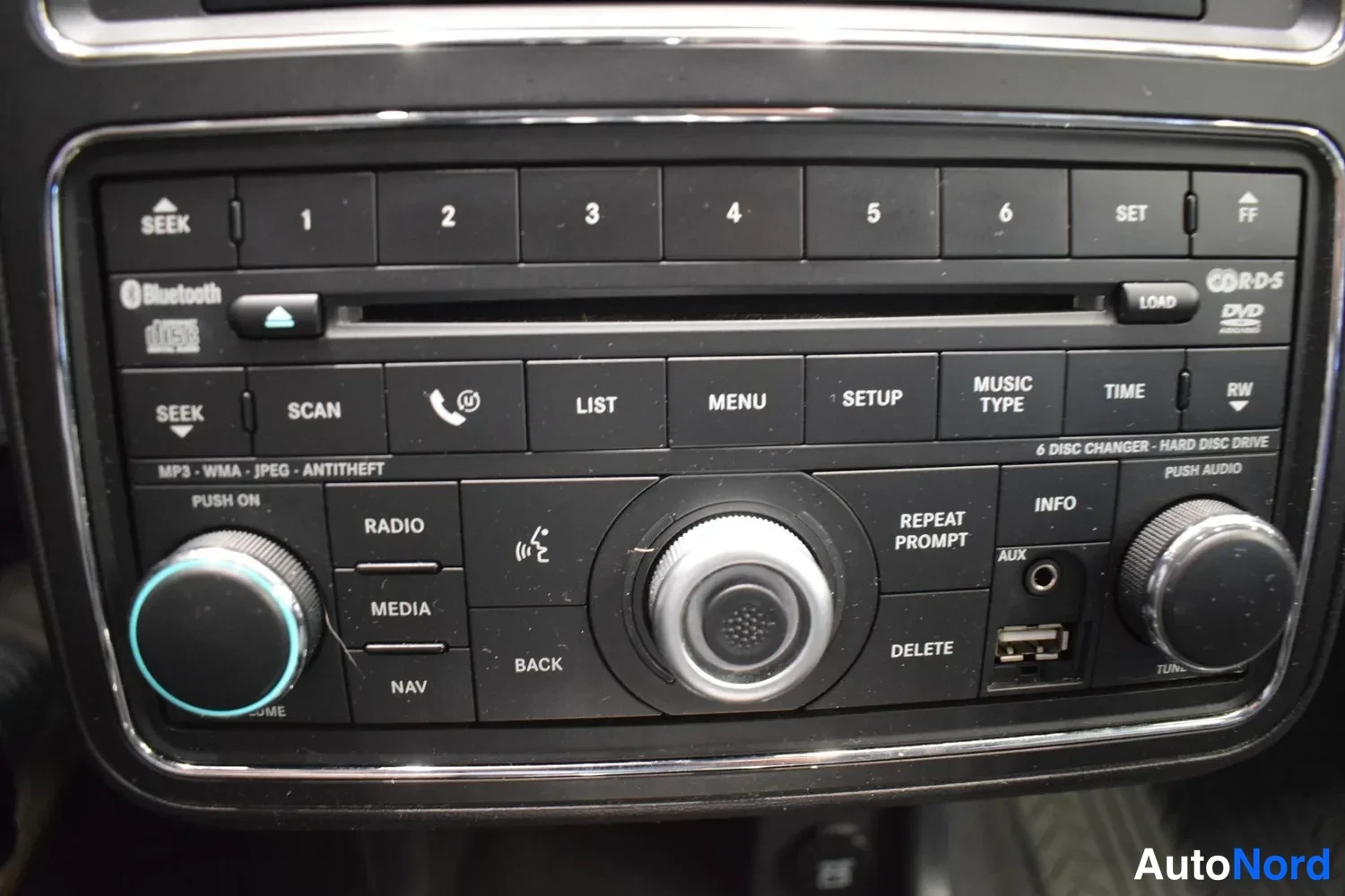 Yksityiskohta: Sisätila: radio/mediayksikkö, jossa Bluetooth-logo, 6 levyä vaihtava CD-lukija ja kiintolevy, AUX- ja USB-liitännät.