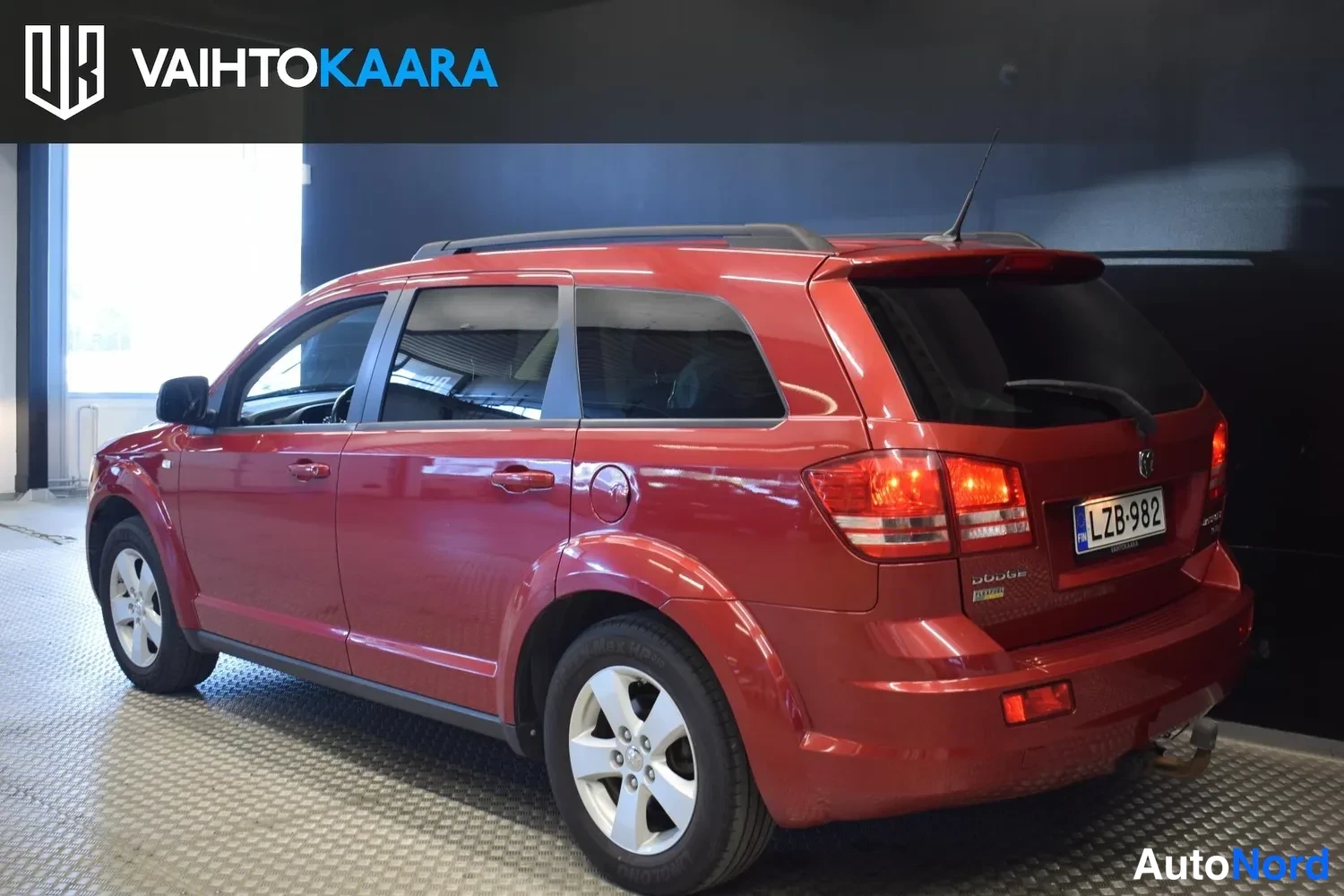 Takaviisto: Punainen Dodge Journey takaa oikealta kolmasosakulmasta, rekisterikilpi näkyvissä.