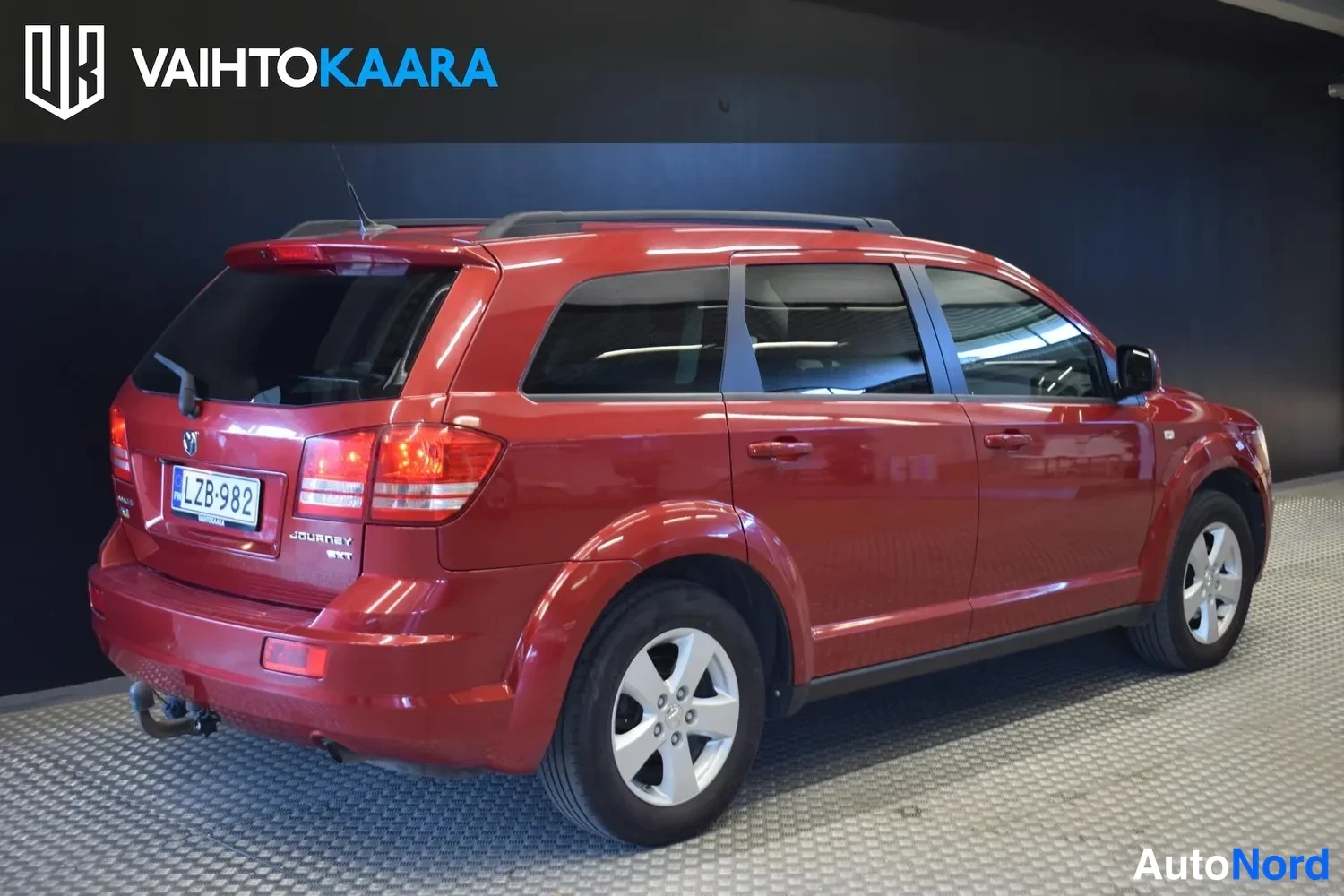 Takaviisto: Punainen Dodge Journey takaa vasemmalta kolmasosakulmasta, perä ja kylki näkyvissä.