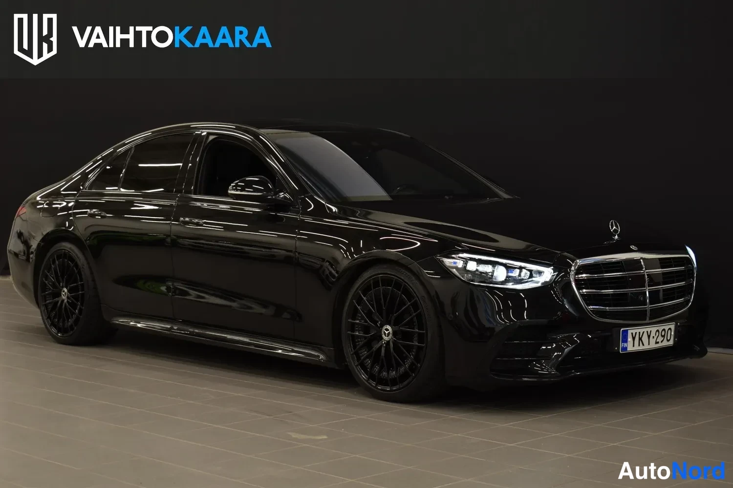 Etuviisto, nokka oikealle: Mustan Mercedes-Benz S-luokan sedanin etukulmanäkyvä kuva oikealta, jossa näkyvät kromikehyksinen etusäleikkö, ajovalot ja rekisterikilpi.