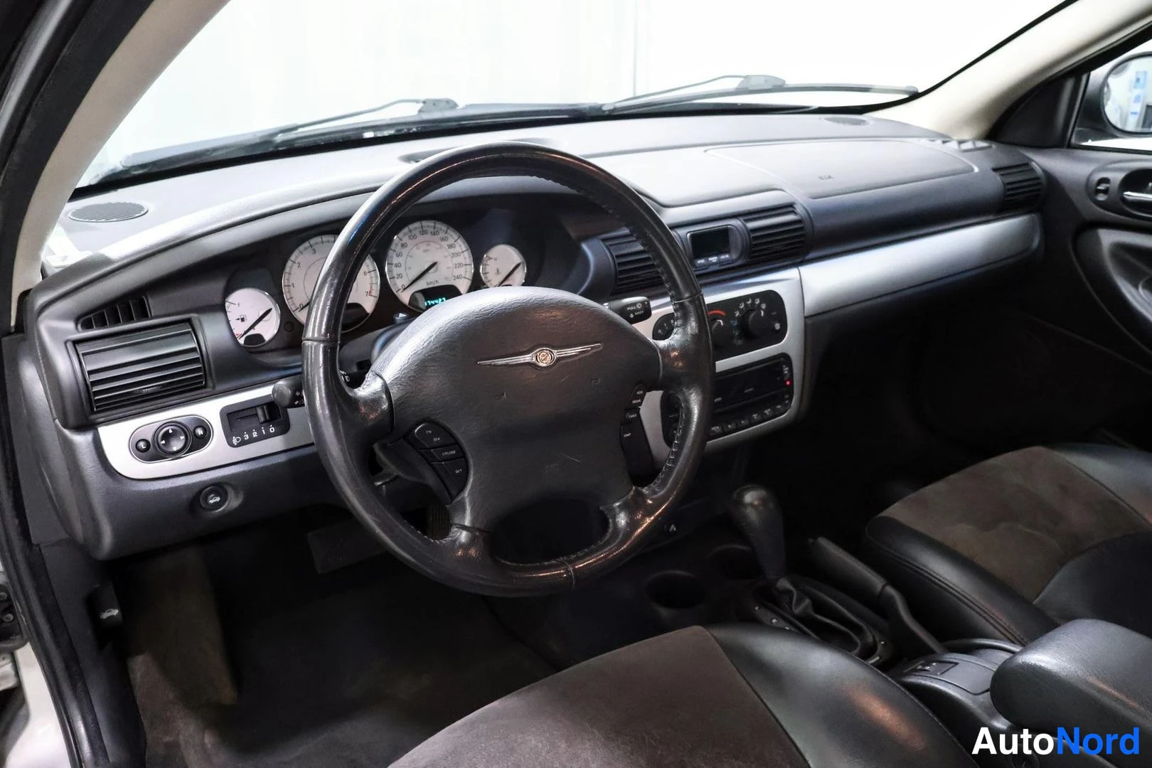 Edestä: Kojetaulu ja ohjauspyörä Chrysler-merkillä, mittaristo ja vaihdevipu näkyvät.