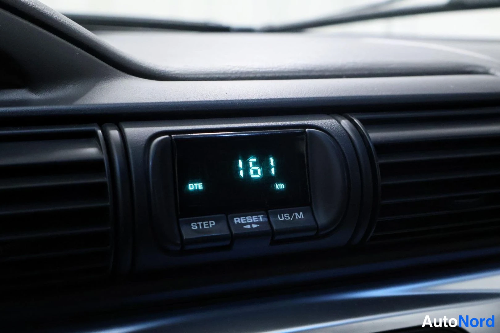 Yksityiskohta: Kojelaudan digitaalinäyttö näyttää DTE-teknologian ilmoittamalla 161 km matkan; STEP, RESET ja US/M-painikkeet näkyvät.