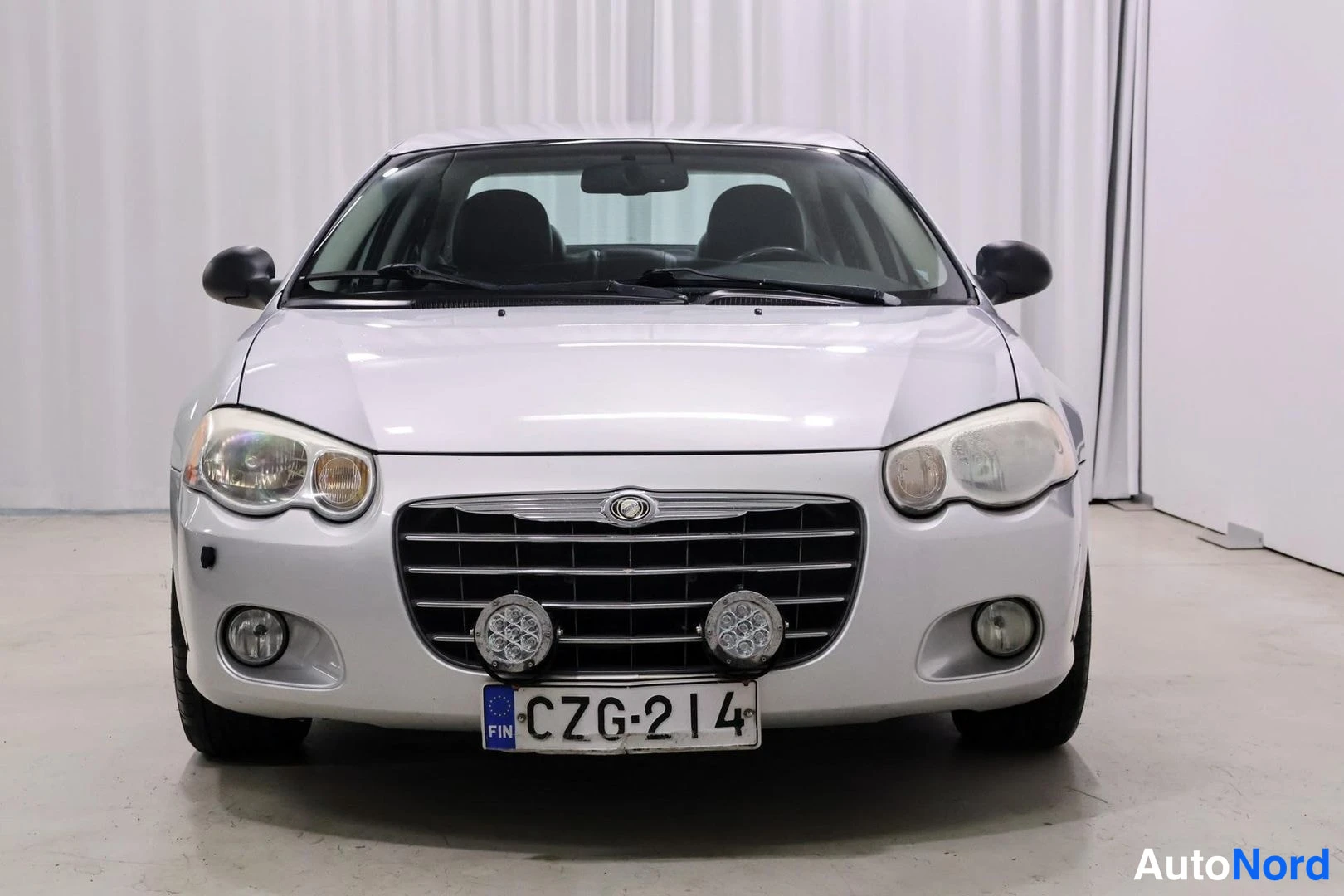 Edestä: Auton keula suoraan edestä: Chrysler-merkitty etusäleikkö, sumu- ja lisävalot, rekisterikilpi.