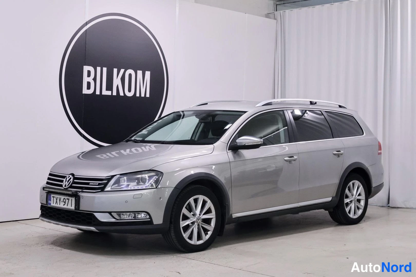 Etuviisto, nokka vasemmalle: Hopeanharmaa Volkswagen Passat Variant farmari etuviistosta vasemmalle kuvattuna studio- tai salonkiympäristössä.