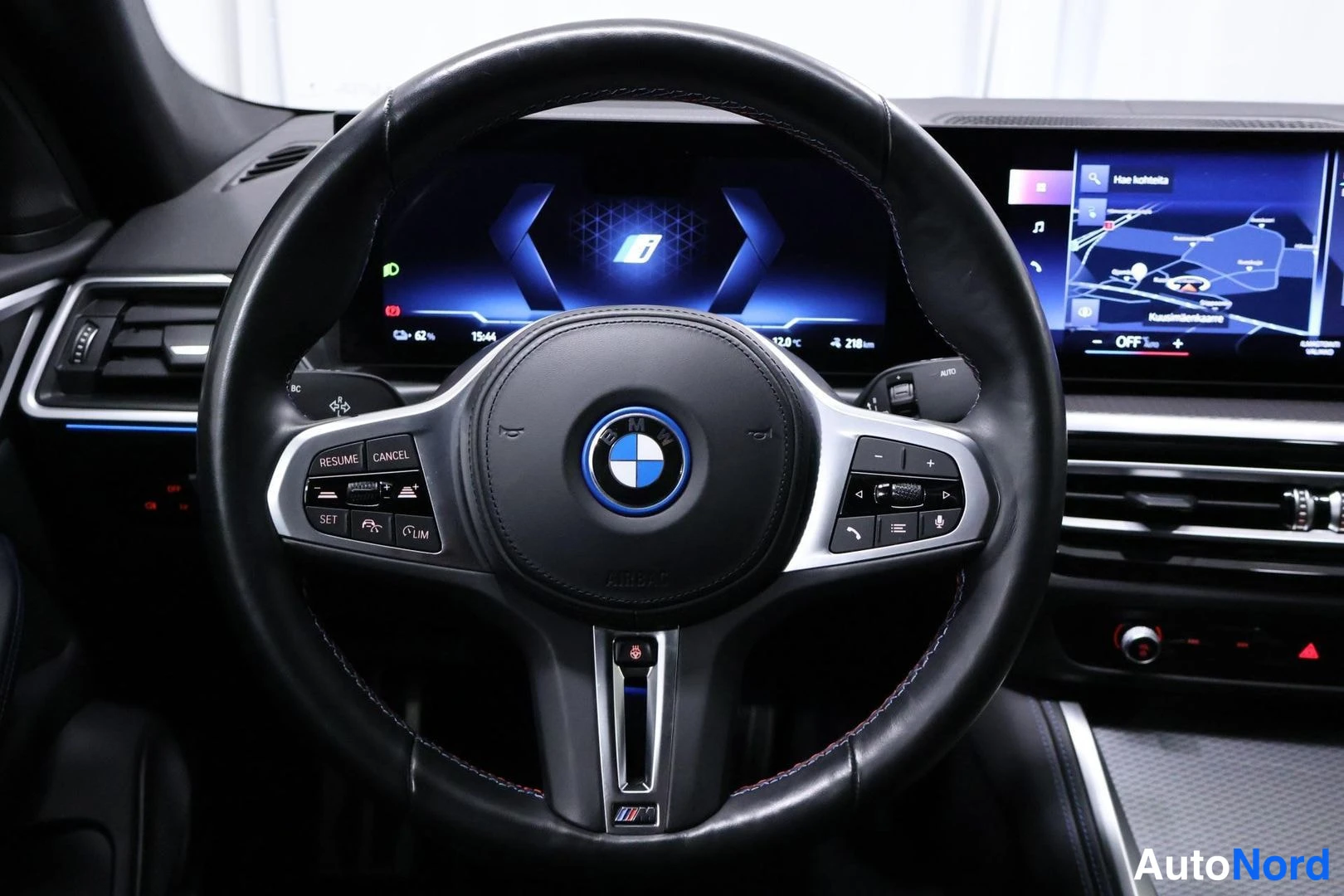 Muu: BMW:n M-ohjauspyörä lähipiirroksessa. Kojelaudan näytöllä näkyy kartta ja ajotietokannan tiedot. Reunalla häivähtaa sininen sisävalaistus.