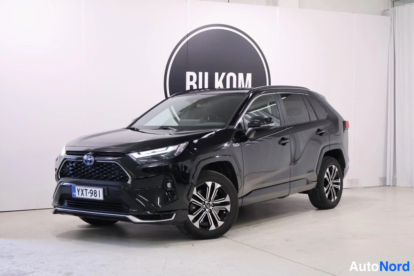 Etuviisto, nokka vasemmalle: Musta Toyota RAV4 -maasturi kulmasta edestä vasemmalta valkoisessa studiossa, rekisterikilpi.