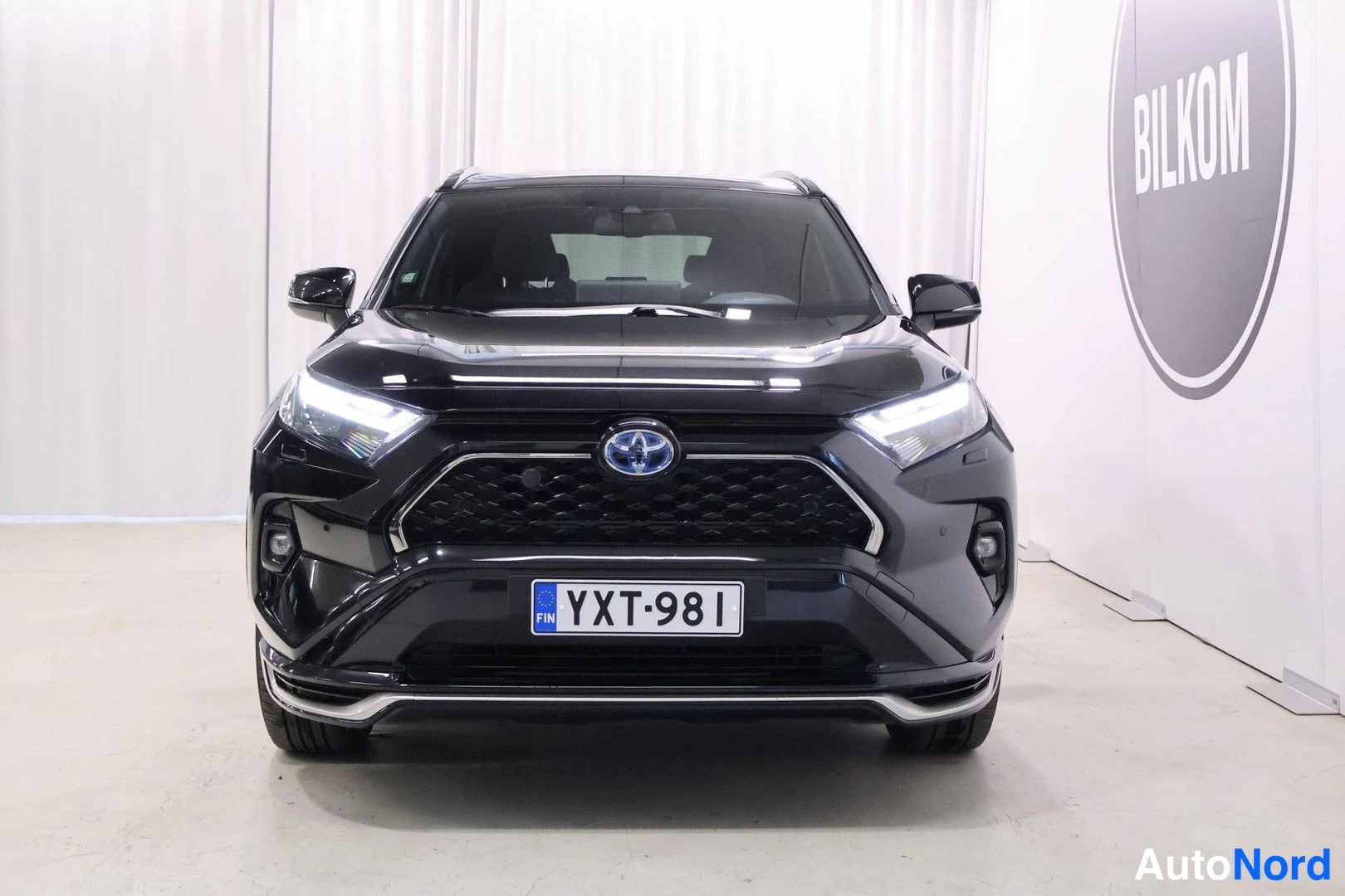 Edestä: Musta Toyota RAV4 -maasturi suoraan edestä, Toyota-merkki säleikössä ja rekisterikilpi.
