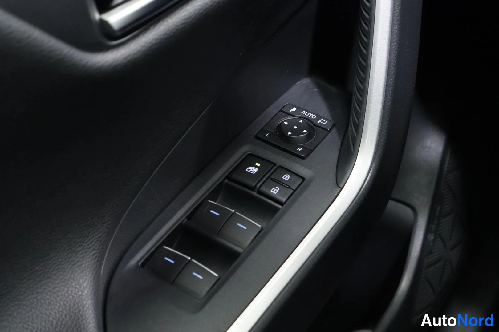 Yksityiskohta: Driver's side door panel control cluster: four power window switches with blue indicator strips and a roof-mounted rear-view mirror with manual folding controls