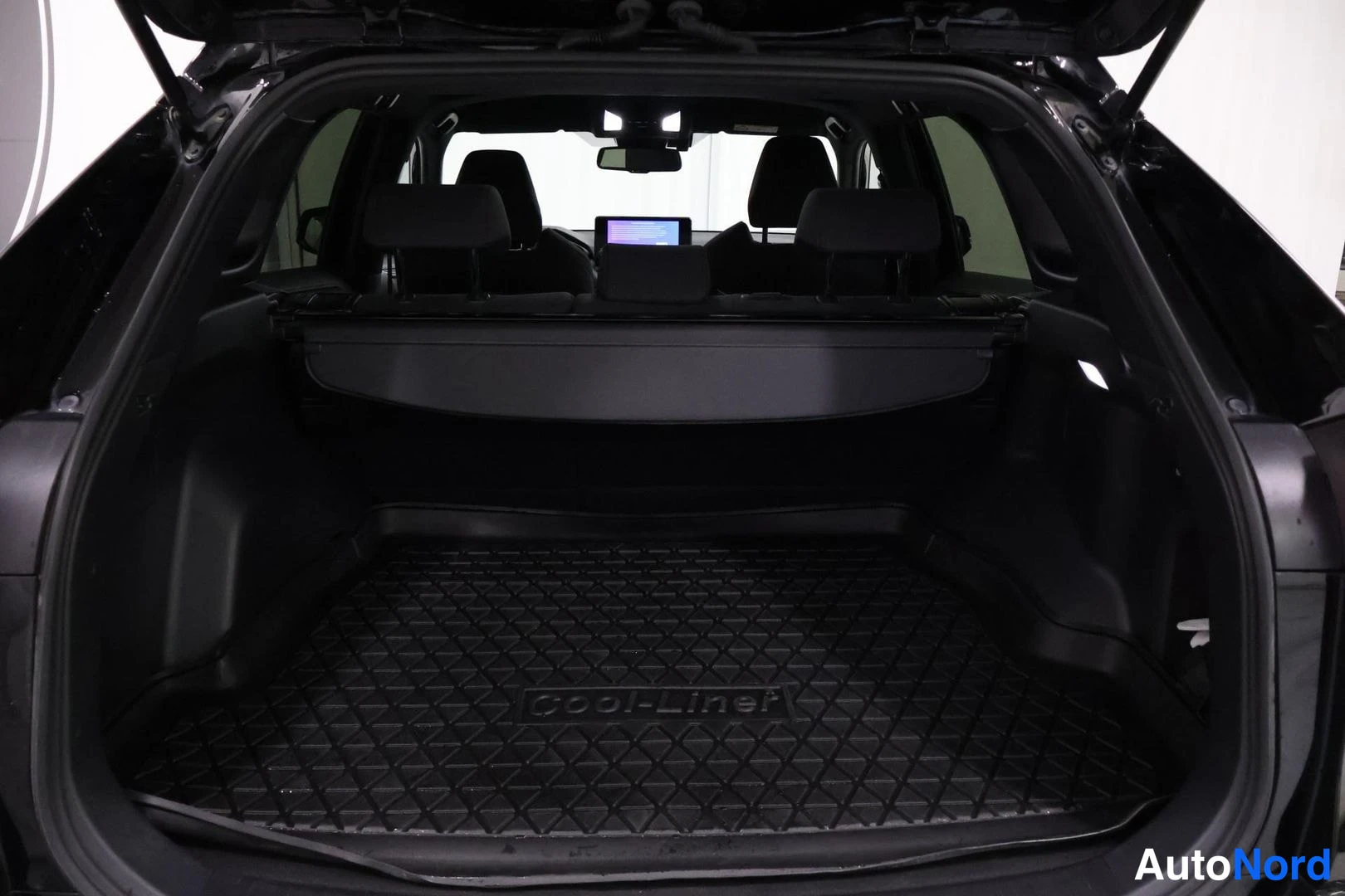 Tavaratila: The cargo area is open showing a black rubber load liner branded with 'COOL-Liner'. A retractable cover conceals storage space below, and the second-row headres
