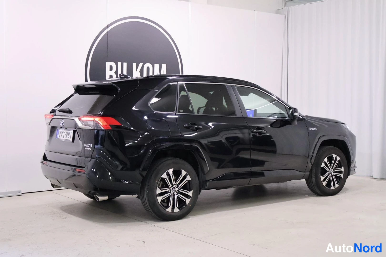 Takaviisto: Takakolmasosa näkyy tummasta Toyota RAV4:sta. Auton takavaloja ja rekisterinumero on selkeästi luettavissa. Takamattojen suojana oleva kaari ja 'HYBRID'-merkint