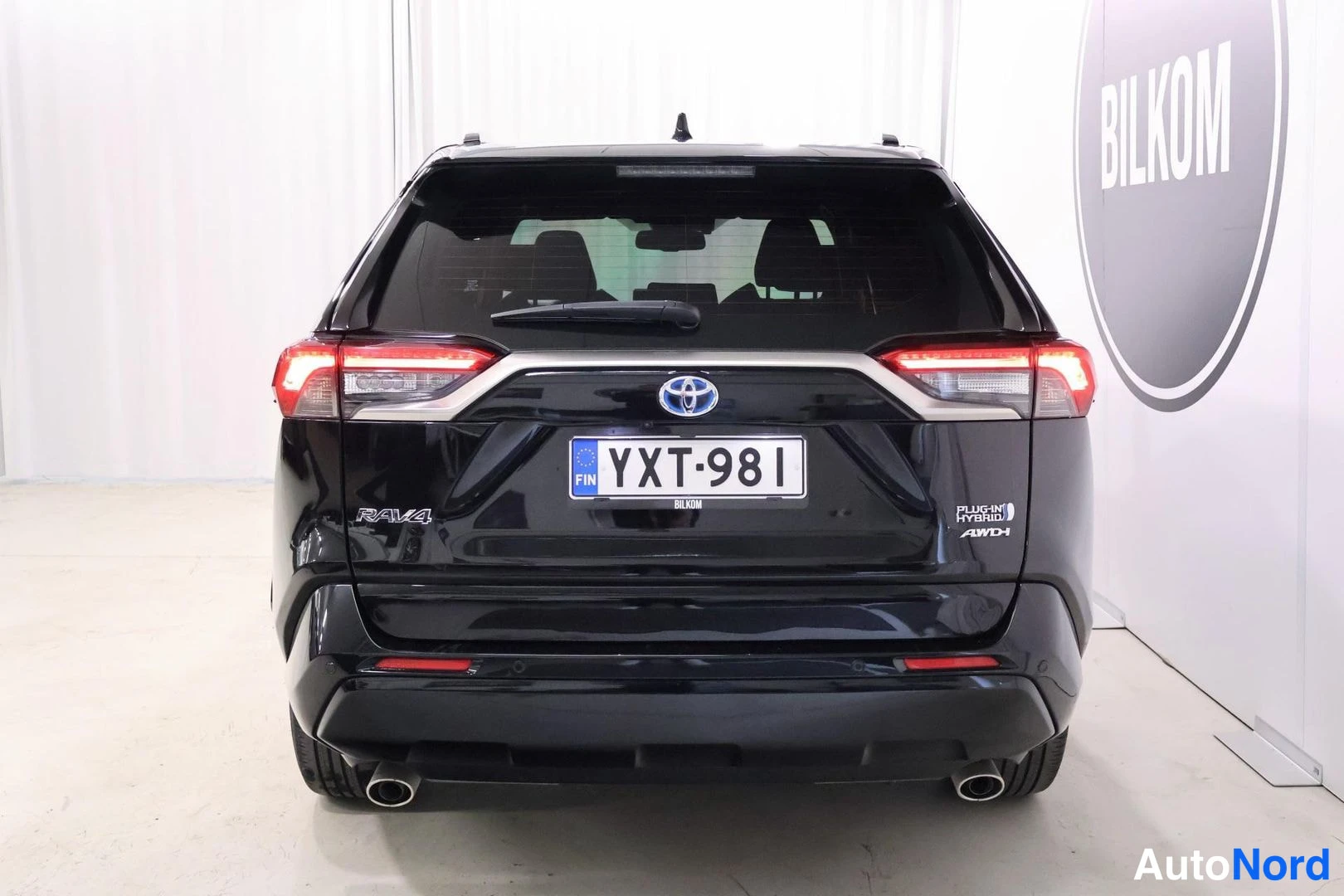 Takaa: Mustan Toyota RAV4:n takaosa suoraan takaa; rekisterikilpi, RAV4-merkintä sekä PLUG-IN HYBRID- ja AWD-tekstit takapaneelissa.