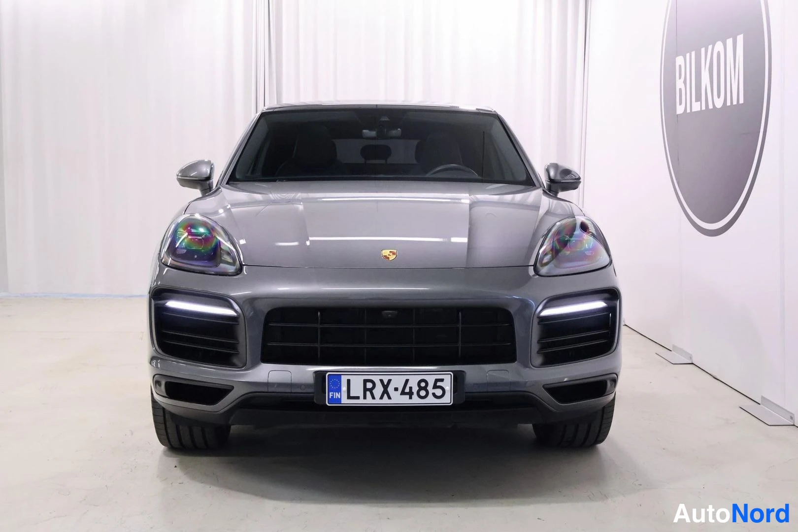 Edestä: Porsche Cayenne Coupé suoraan edestäpäin kuvattuna; ajovalot ja etupuskurin valoisaiden viivat päällä, rekisterikilpi.