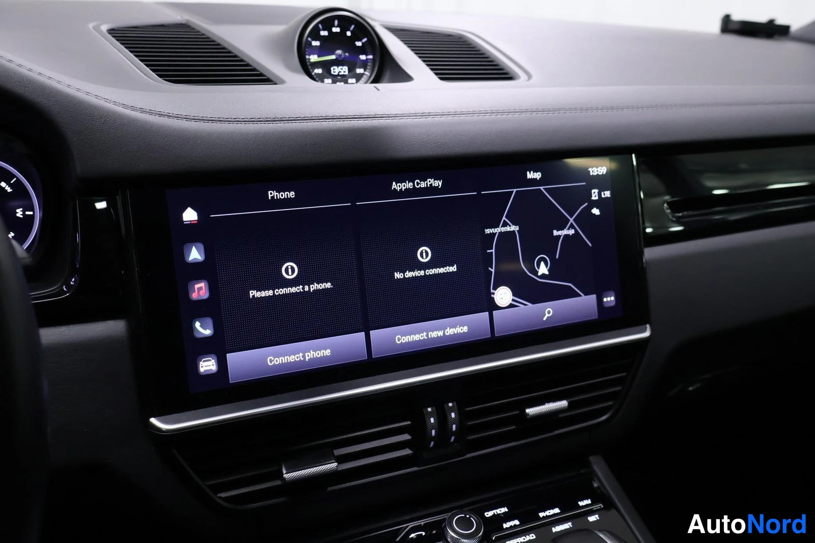 Ohjaamo: Wide dashboard display showing Apple CarPlay interface with a map and phone connection status. An analog clock is mounted centrally above the screen.