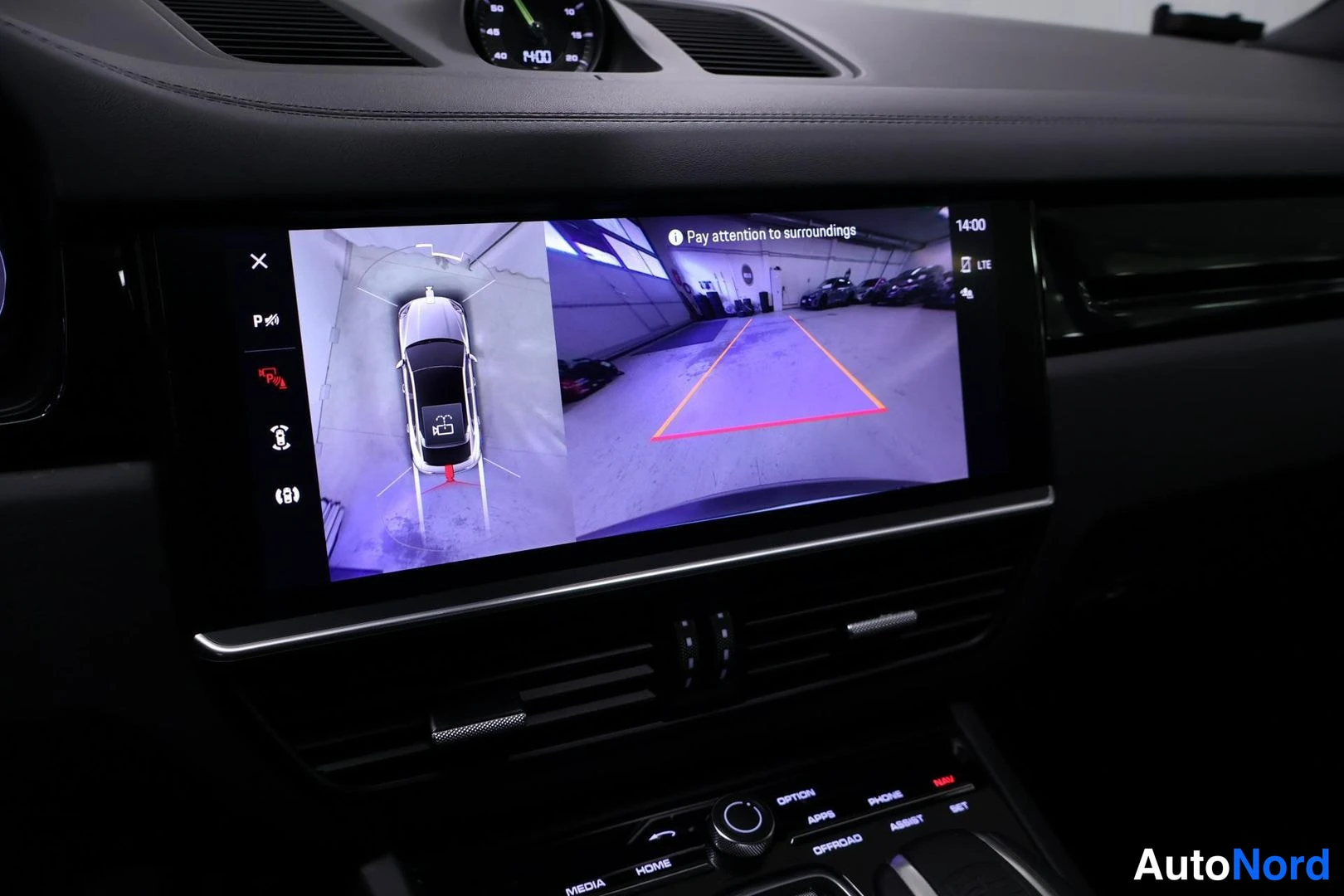 Ohjaamo: Interior dashboard shot showing a widescreen infotainment display active with a rear-view camera and surround view (360) graphic overlay. Below the screen are c