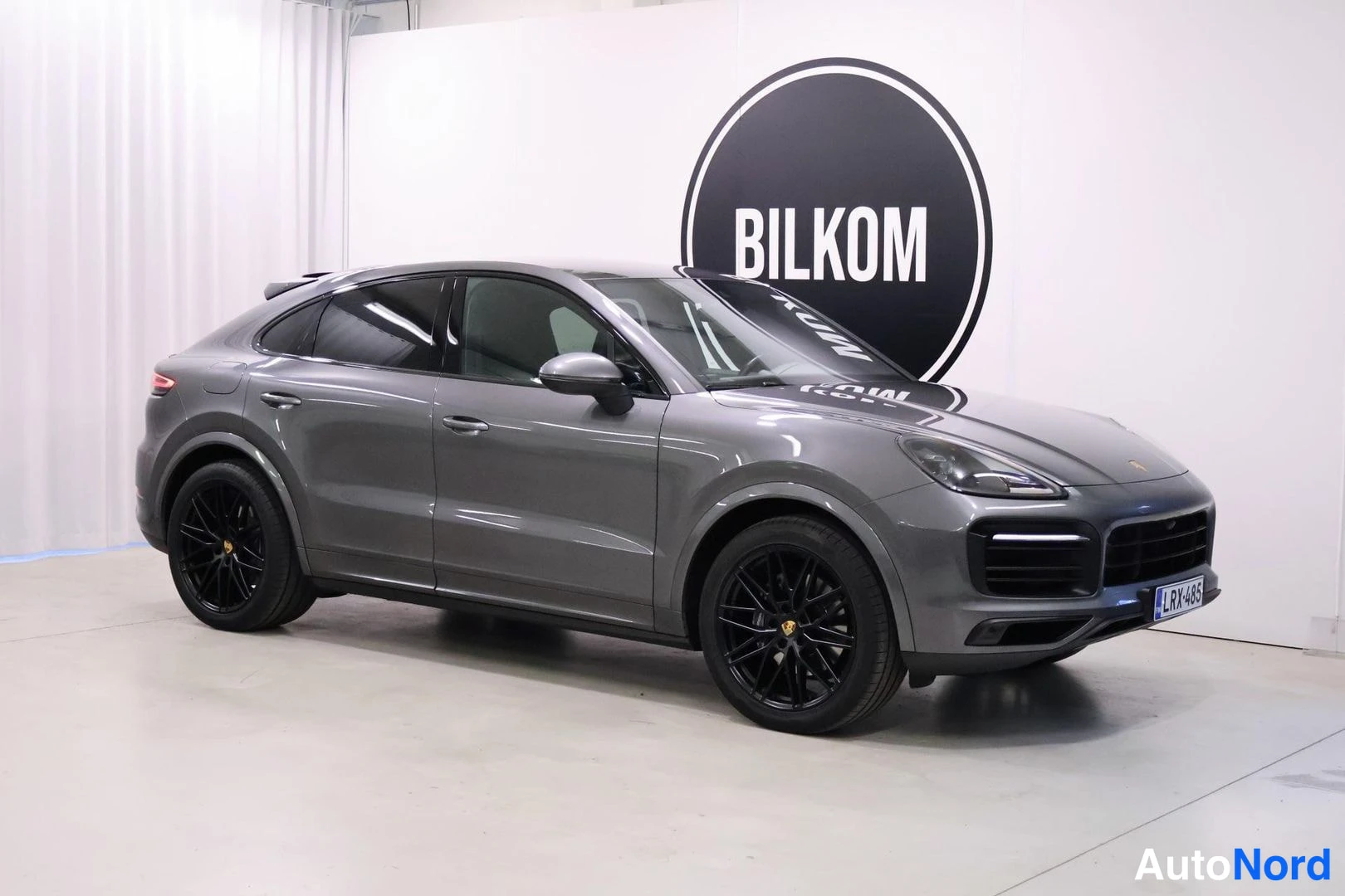 Etuviisto, nokka oikealle: Tummanharmaa Porsche Cayenne Coupé etukulmakuvassa, keula oikealla; mustat kevytmetallivanteet ja rekisterikilpi.
