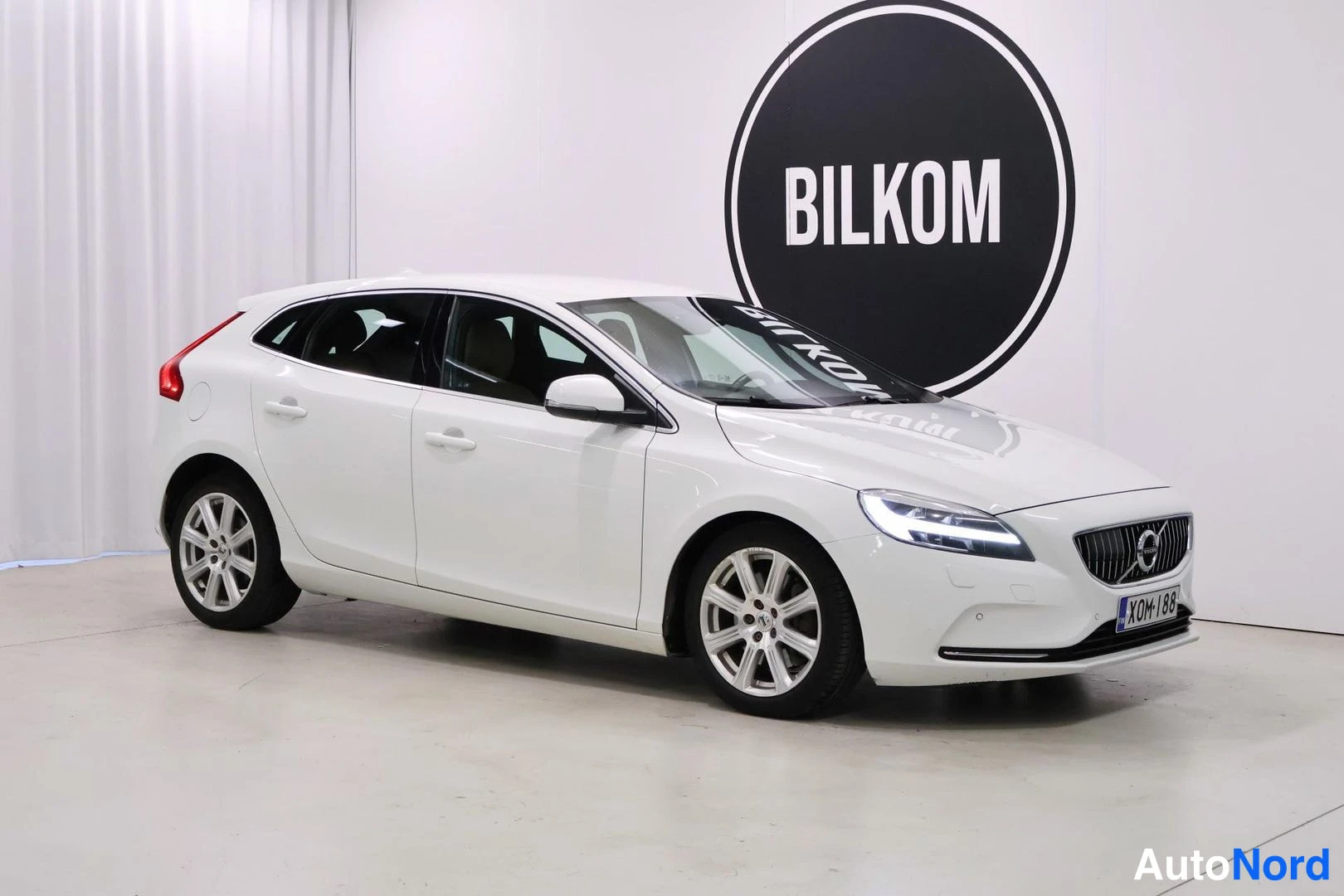Etuviisto, nokka oikealle: Valkoinen henkilöauto etukulmasta oikealle kuvattuna.