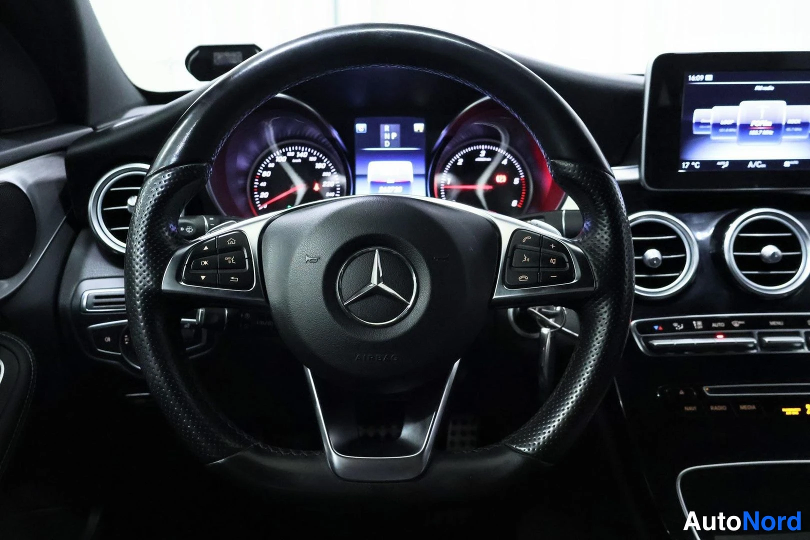 Muu: Lähikuva Mercedes-ohjauspyörästä ja mittaristosta, näytöllä automaattivaihteiston vaihetiedot.