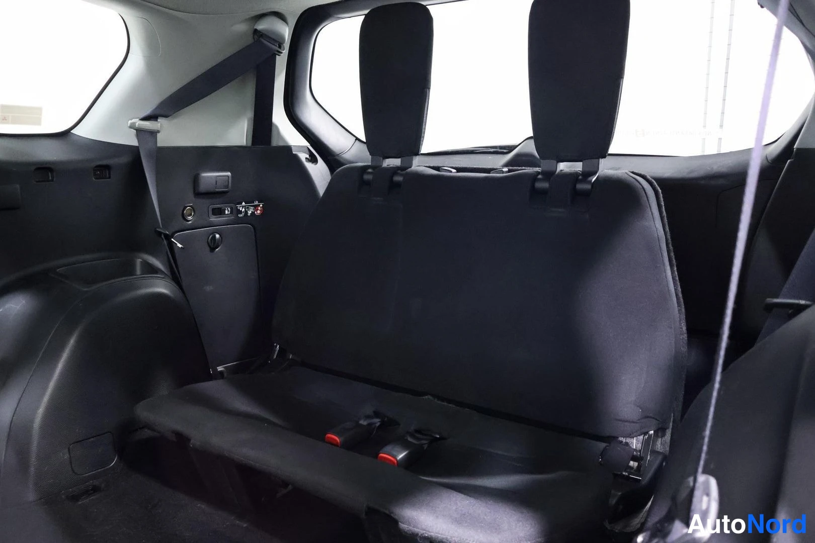 Tavaratila: Reclined black fabric third row seat in cargo area showing ISOFIX anchors on side panel and folded second row backrests ahead