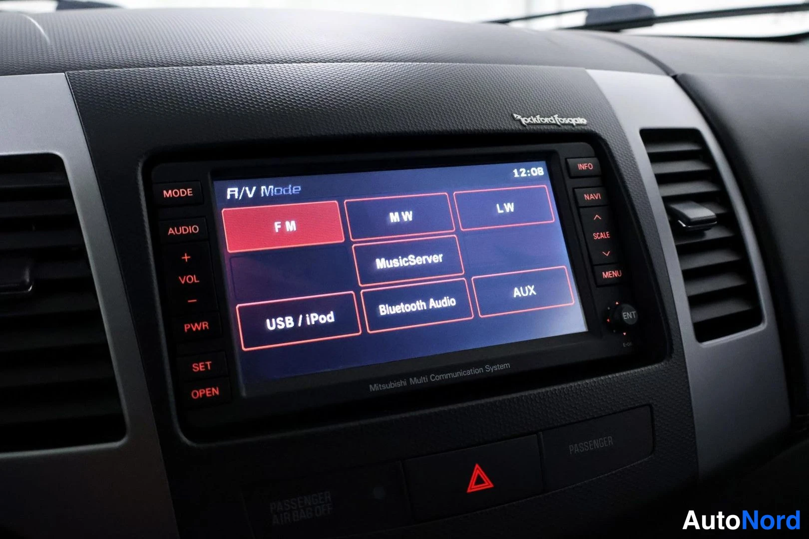 Yksityiskohta: Lähikuva keskikonsolin kosketusnäytystä, jossa on toimintoja kuten FM-radio, MusicServer ja USB/iPod. Näytön yläpuolella lukee Rockford Fosgate ja alapuolella M
