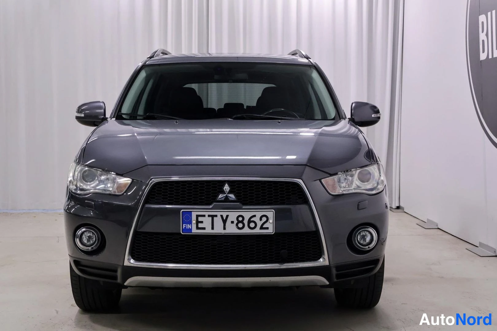 Edestä: Etukuvassa auto täytenä; vasemmalla ja oikealla puolella ovat samankokoiset etuvalot, keskellä grilli, jossa Mitsubishi-logo, alapuolella sumuvalot ja suuri rek
