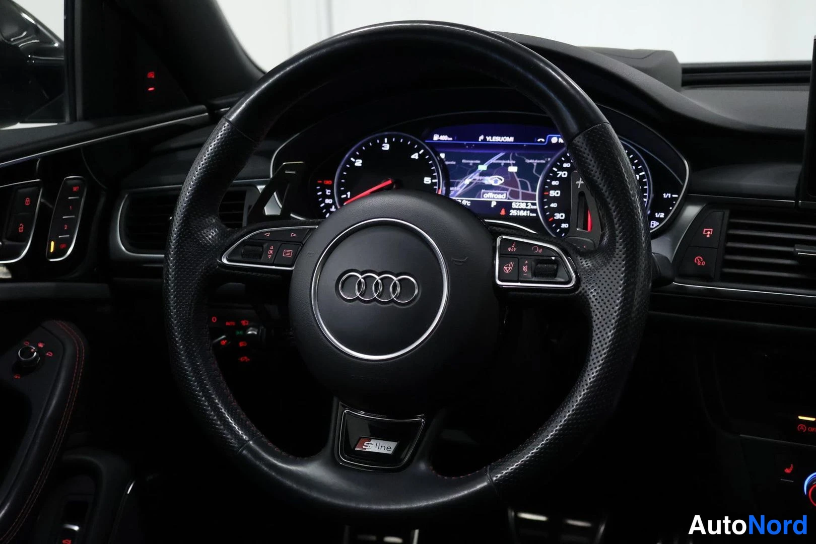 Muu: Ajon paikan ohjaamo: Audi-ohjauspyörä ja digitaalinen mittaristo, jonka näytöllä navigointikartta.