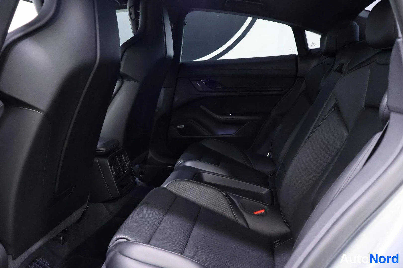 Takaistuimet: Interior rear seating area showing black leather rear seats and door panel with window switches.
