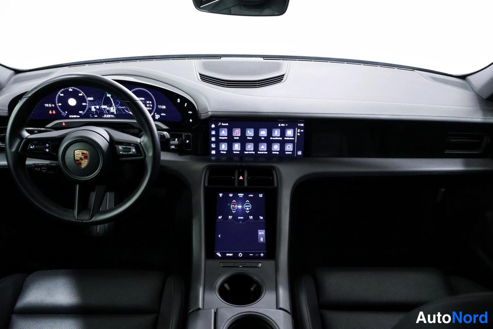 Ohjaamo: Dashboard view showing instrument cluster, Porsche logo on steering wheel, upper infotainment screen displaying app icons, lower climate control touchscreen, an