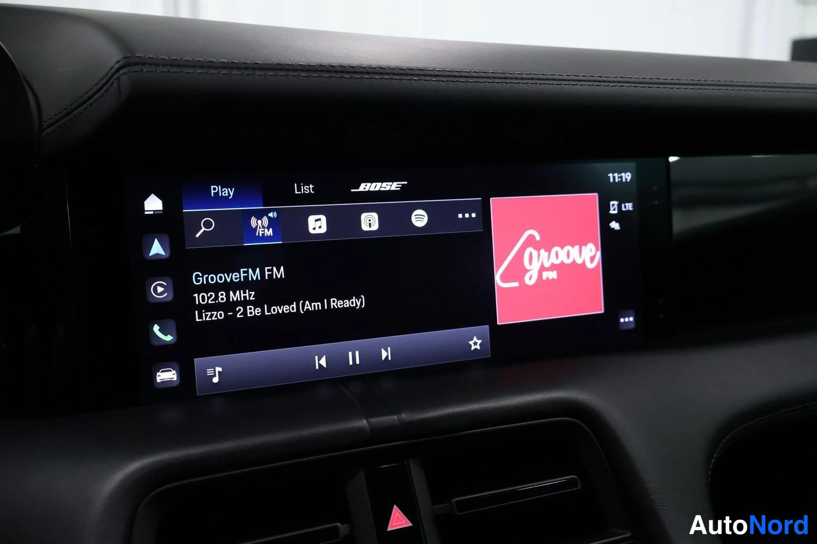 Ohjaamo: Car radio screen playing FM station 102.8 MHz (GrooveFM) with artist Lizzo song title displayed; Bose premium audio brand name visible on screen bezel.