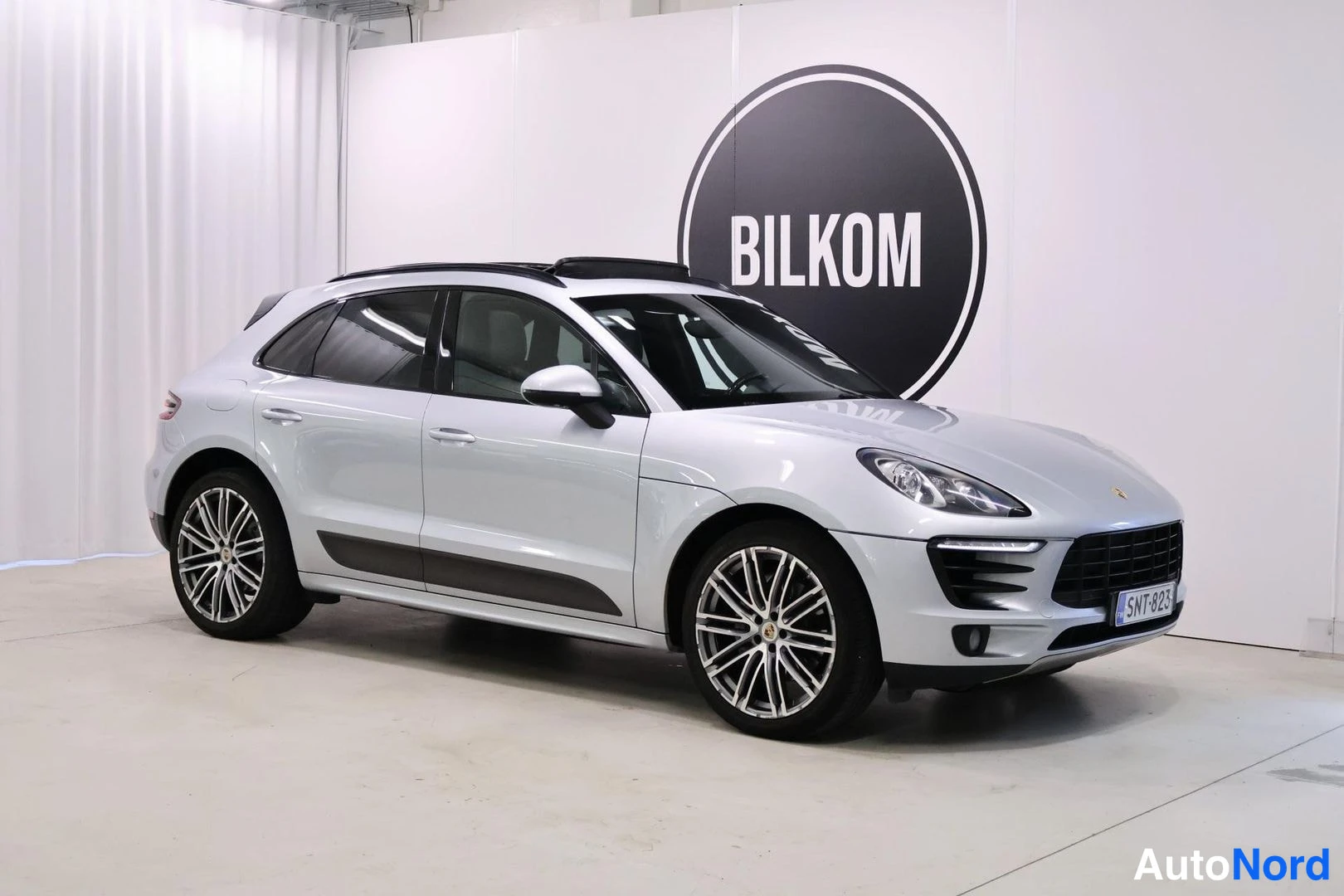 Etuviisto, nokka oikealle: Hopeanvärinen Porsche Macan etukulmasta oikealta, rekisteritunnus.