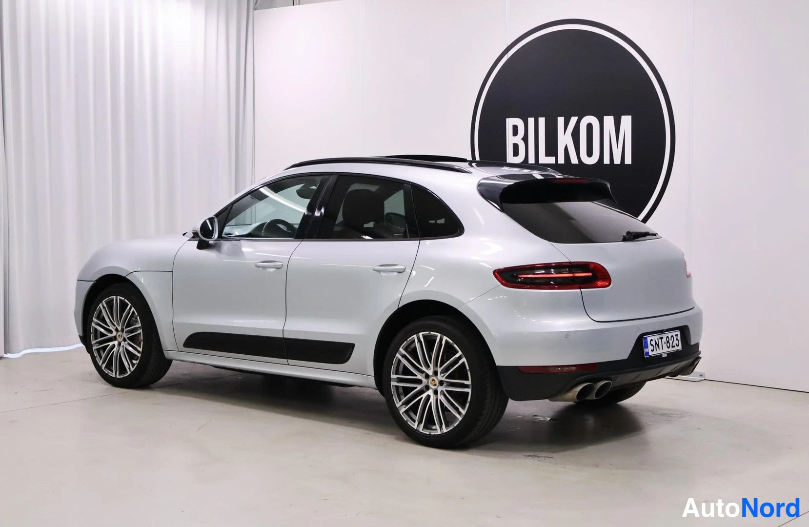 Takaviisto: Silver Porsche Macan rear three-quarter view showing the boot lid and left flank against a white studio background