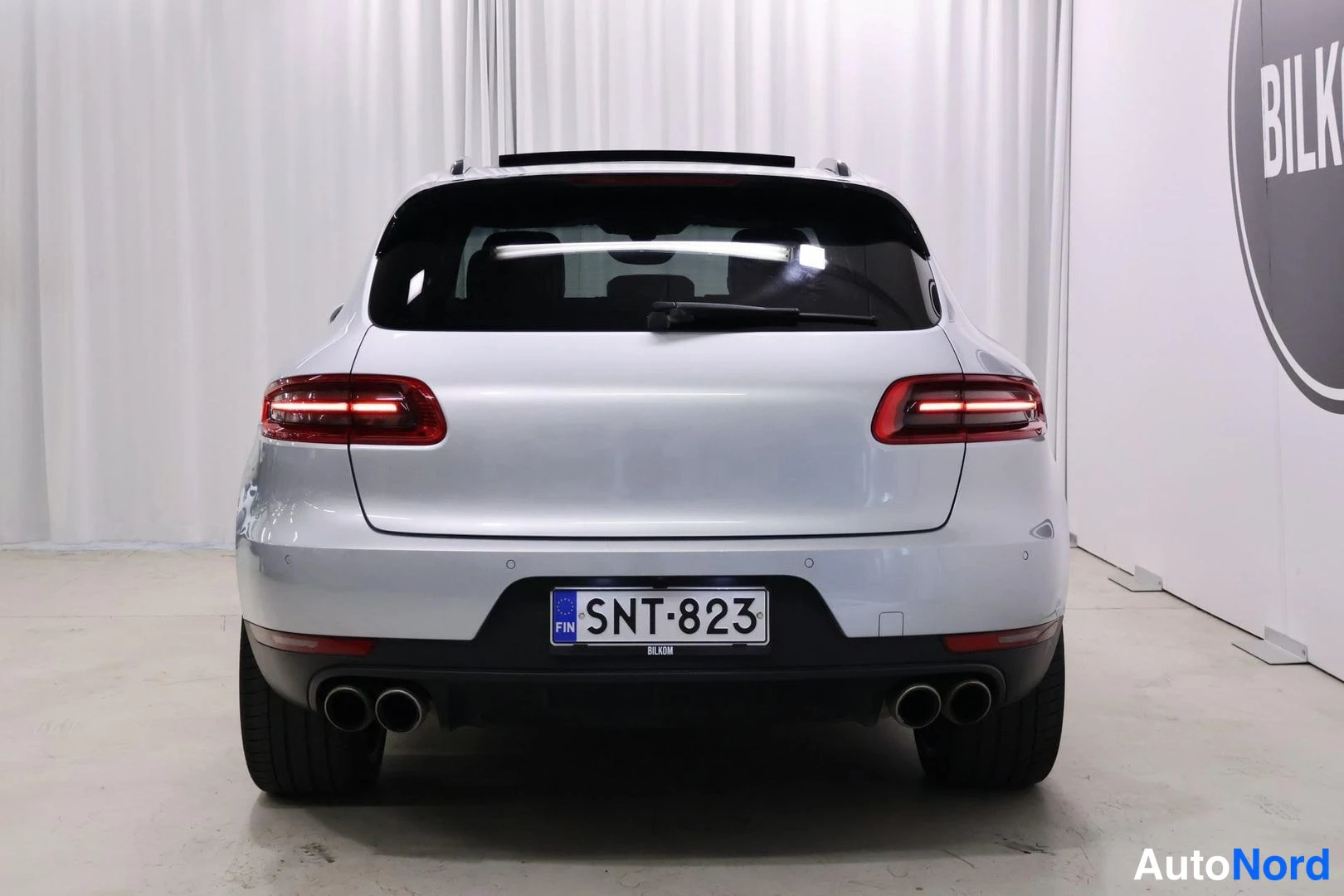 Takaa: Rear view of a silver SUV with dual exhausts and license plate mounted on the bumper