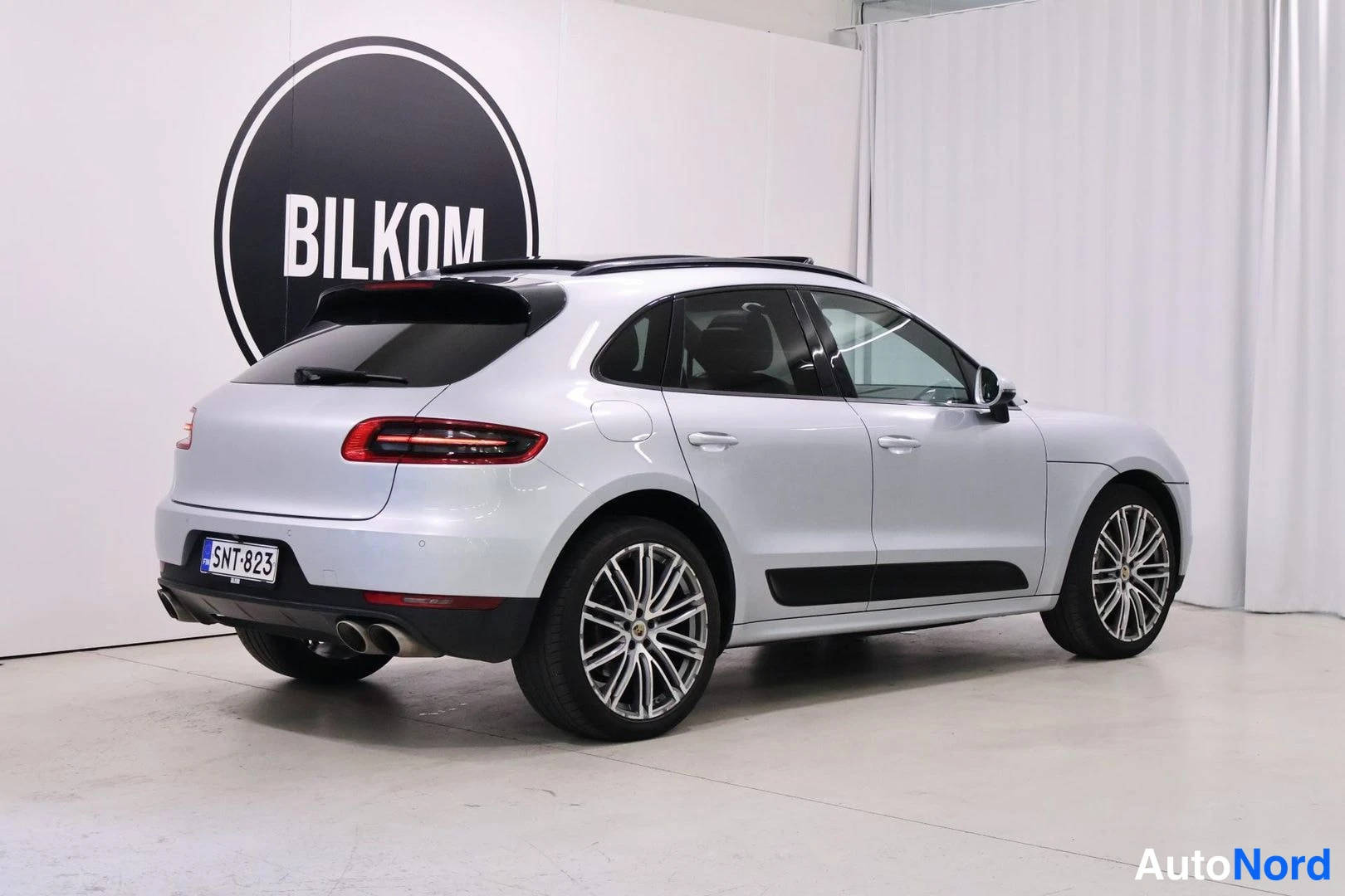 Takaviisto: Porsche Macan -takakolmannejakuva valkoisella sisustuseinällä ja BILKOM-logolla