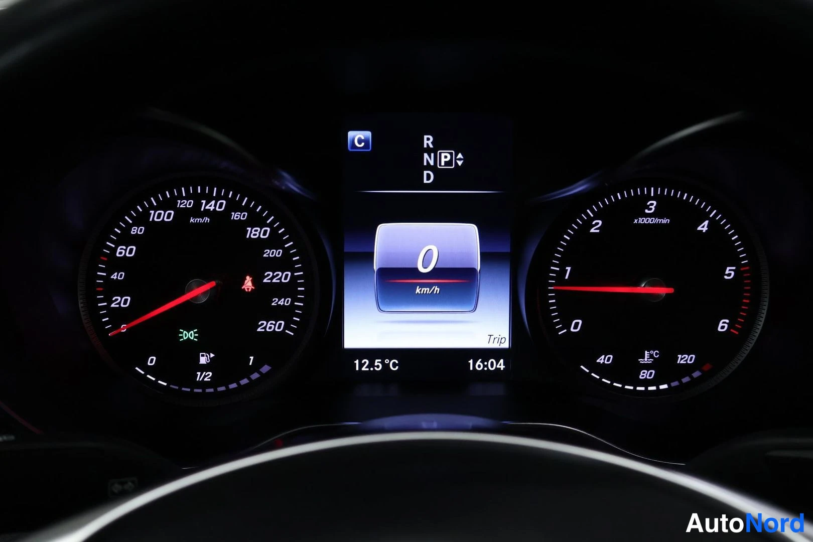 Yksityiskohta: Instrument panel featuring two analog gauges flanking a central vertical digital information screen. The left gauge indicates speed up to 260 km/h with visible