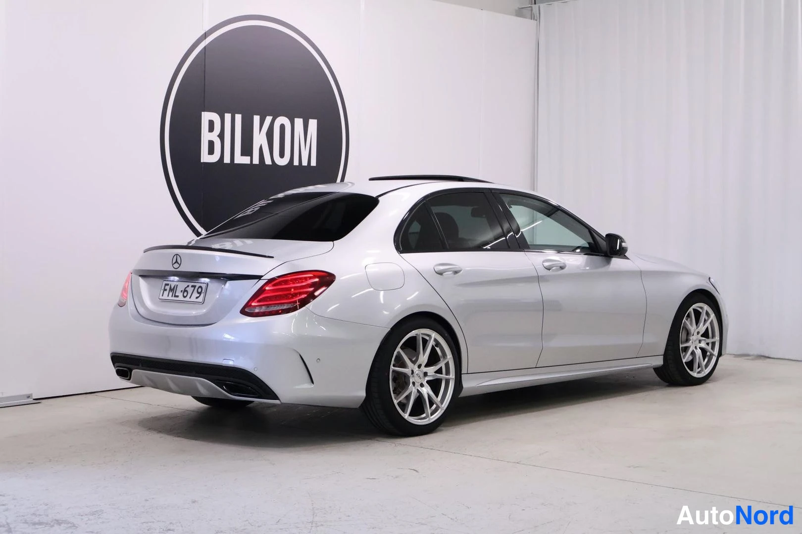Takaviisto: Silver Mercedes-Benz C-Class sedan photographed from rear three-quarter angle showing entire right flank and rear face including tail lights and boot lid. Sunro
