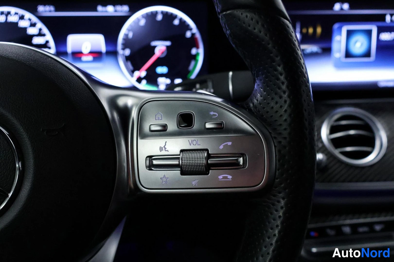 Yksityiskohta: Close-up of the steering wheel's right-side control paddle with buttons for voice command, menu navigation and phone functions.
