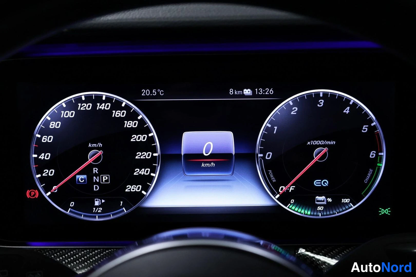 Yksityiskohta: Digital instrument cluster displaying speedometer at zero, tachometer, temperature reading of 20.5 C, battery charge level, gear selection (D) and fuel level in