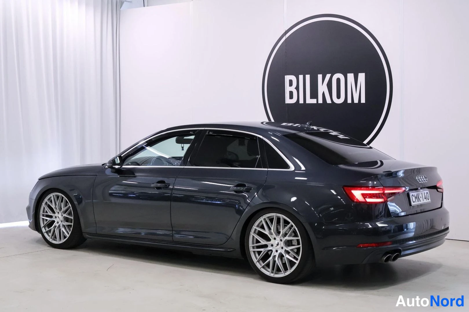 Takaviisto: Tummanharmaa Audi A4 -sedan takakulmasta vasemmalta, kaksiosainen pakoputki ja hopeat vanteet.