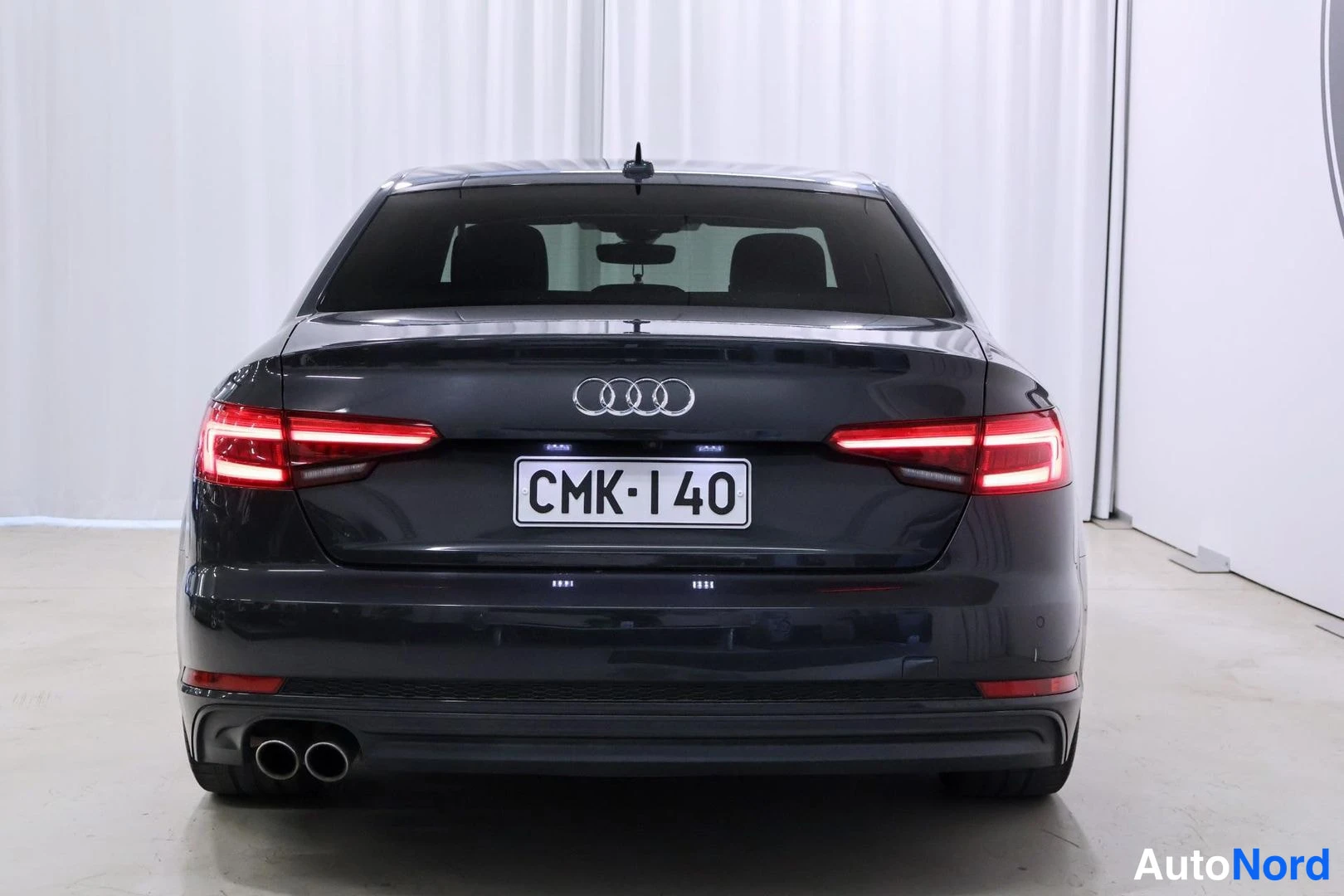 Takaa: Tummanharmaa Audi A4 -sedan takaosa suoraan takaa, rekisteritunnus, kaksoispakoputki.
