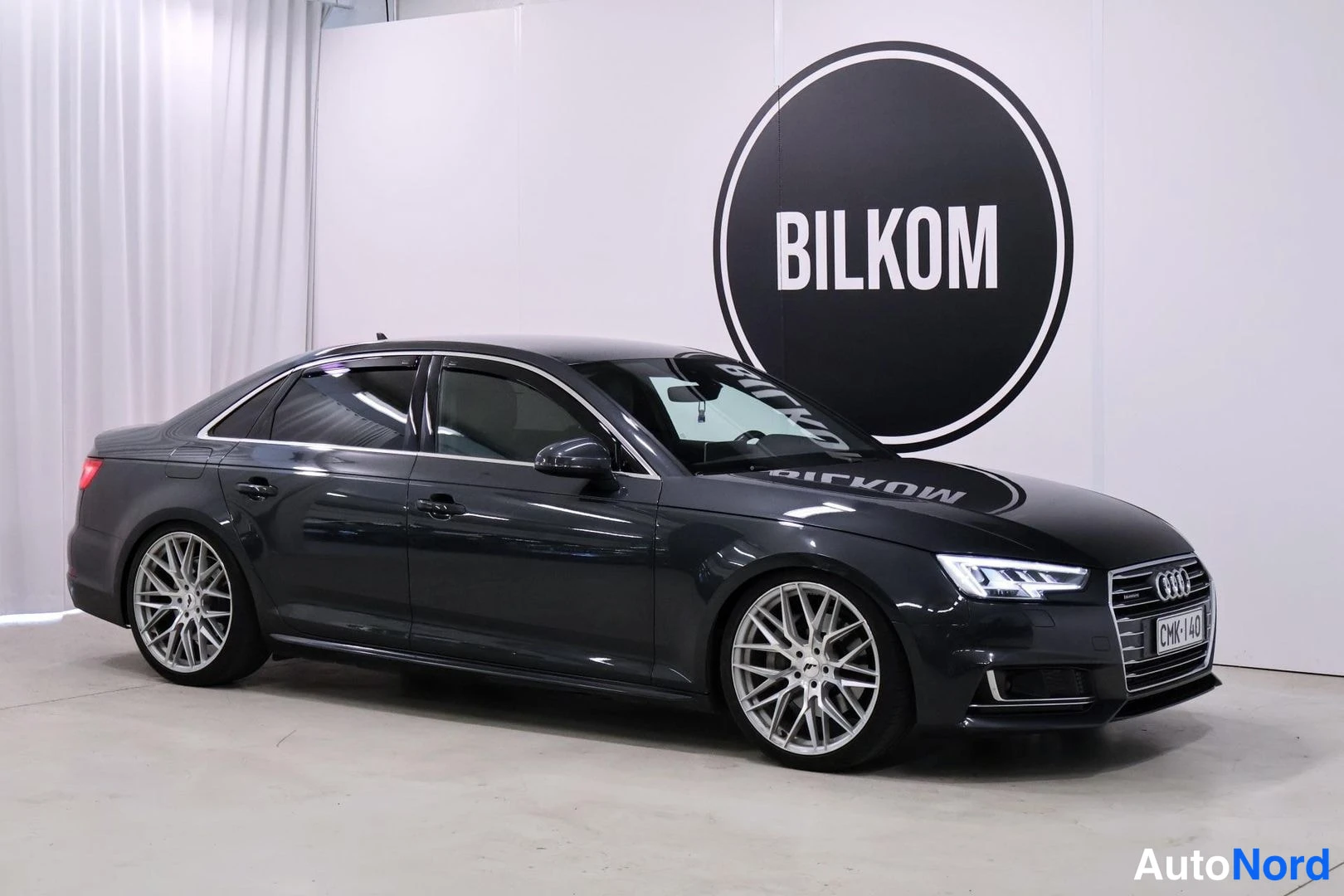 Etuviisto, nokka oikealle: Musta Audi A4 sedanin etusivu kolmannelta kuvattuna studiossa, jossa on LED-ajovalot ja hopeiset vanteet.