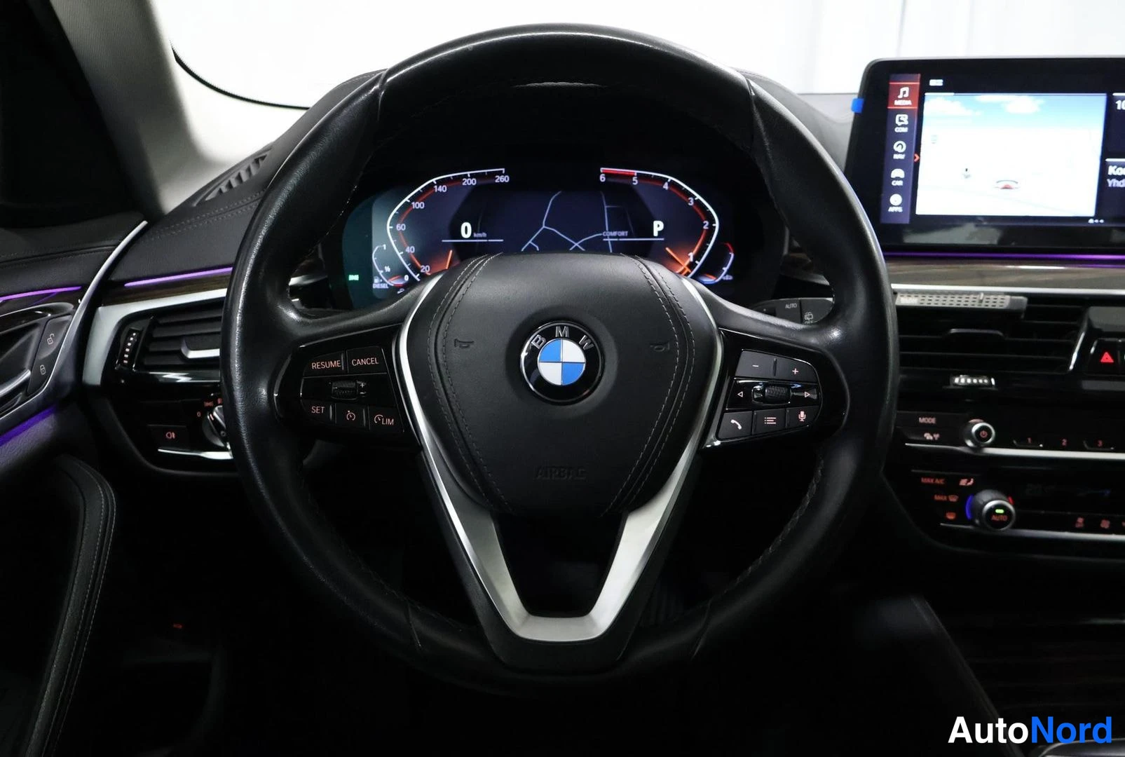 Muu: BMW-ohjauspyörä ja digitaalinen mittaristö, taustalla keskusnäyttö.