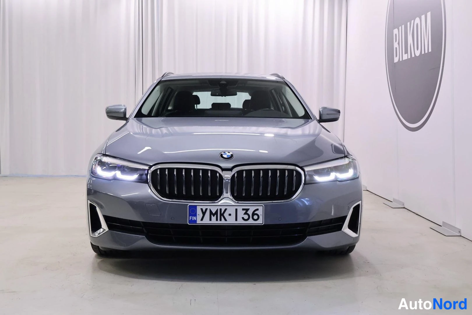 Edestä: BMW 5 -farmari harmaana suoraan edestä, rekisterikilpi.