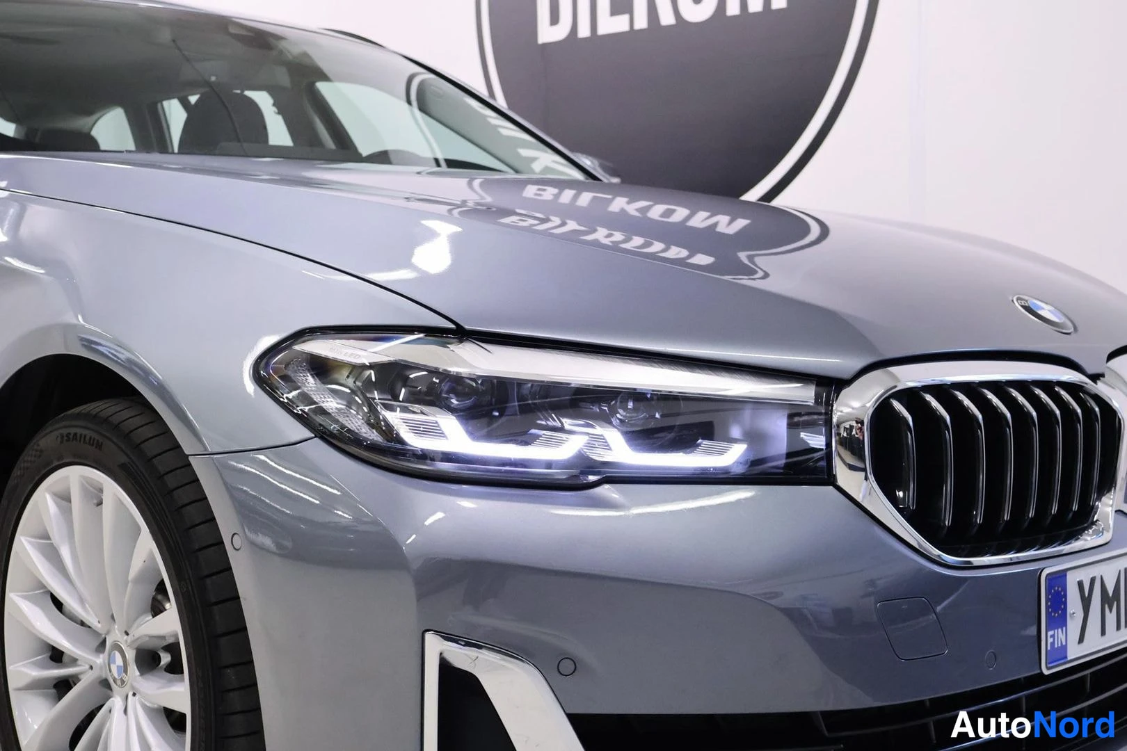 Etuviisto, nokka oikealle: Auton etuosan lähikuva: BMW-mallin etuosa, LED-ajovalot ja munuaistyyppinen etusäleikkö, hopeanharmaassa maalissa.
