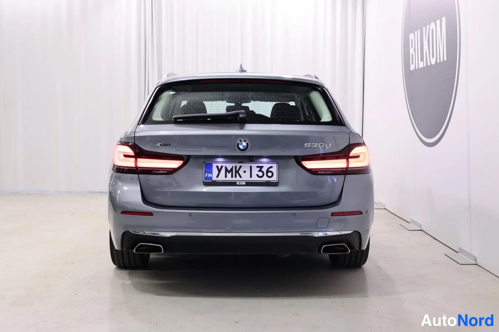 Takaa: Sinertävänharmaan farmariauton takanäky, rekisterikilpi, BMW-merkki ja 530d-tunnus takaluukussa.