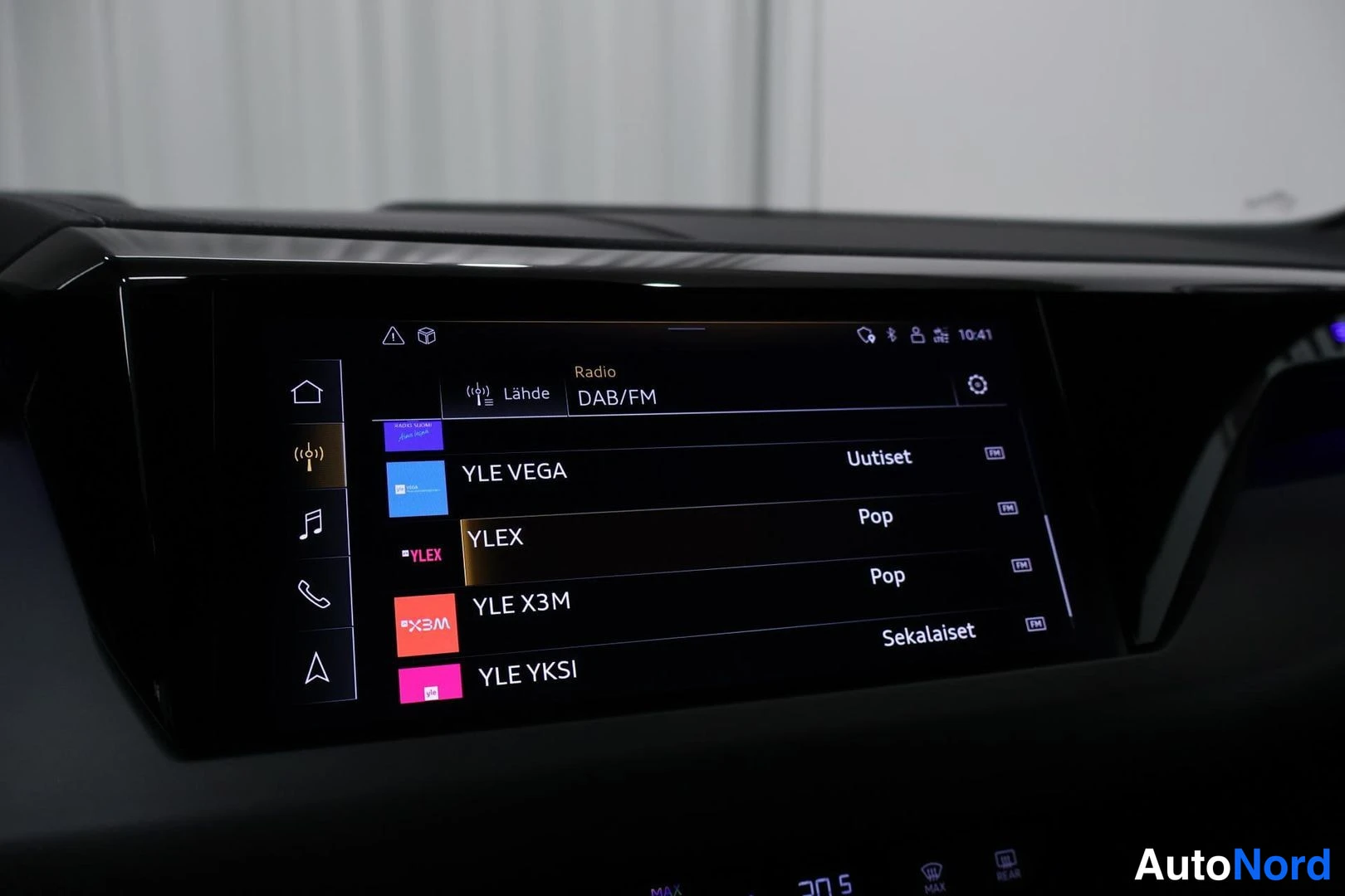 Yksityiskohta: Auton kojelaudan kosketusnäyttö, jossa on radiovalikko: DAB/FM -lähde ja kanavalistaus YLE VEGA, YLEX, YLE X3M ja YLE YKSI.