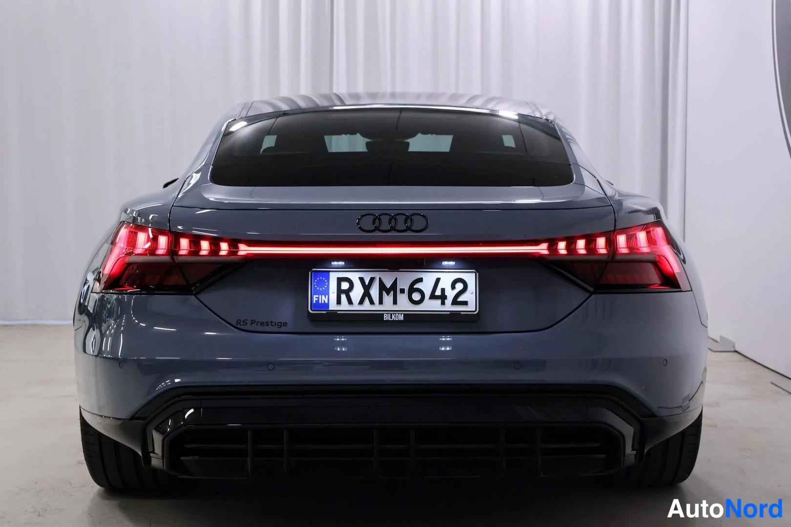 Takaa: Audi e-tron GT:n takaosa suoraan takaa, punainen valoviiva, musta takapuskuri ja diffuussori, rekisteri.
