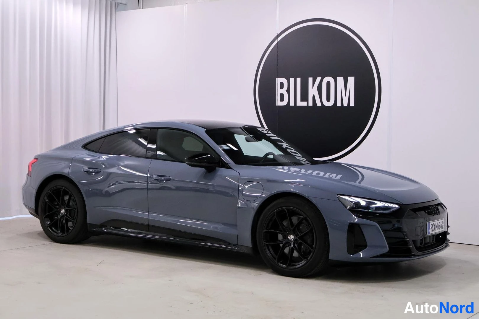 Etuviisto, nokka oikealle: Sinertävänharmaa Audi e-tron GT etuviistosta kuvattuna oikealta: tumma katto, mustat vanteet ja nokka kuvan oikeassa reunassa.